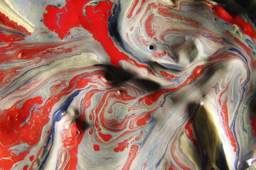 Pintura de acrìlico y aceite de canola en agua flotando en la superficie, en colores rojos, grises...