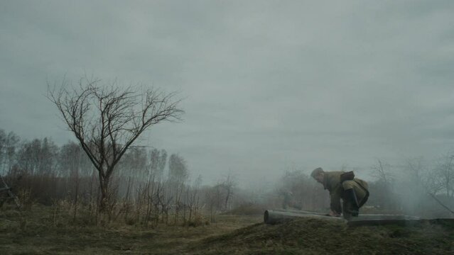 Side view long slowmo of people wearing Red Army uniforms taking part in WW2 reenactment getting out of trench and running along battlefield with rifles in handsSide view long slowmo of people wearing