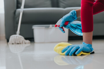 young woman holding cleaning supplies Close-up shot of girl wearing gloves cleaning the area of the house or office. cleaning concept