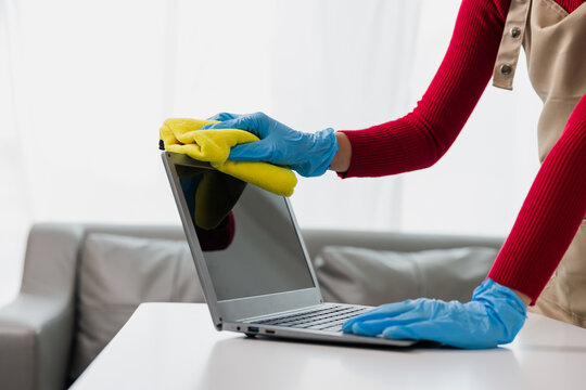 Female hands cleaning laptop computer in office room, desk Young woman using computer, cleaning concept