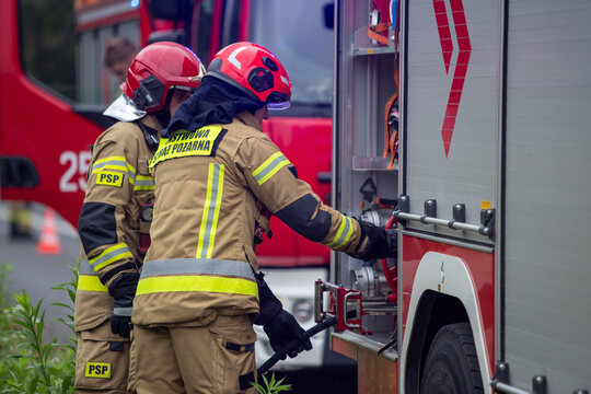 Strażacy podłączający wąż. Straż pożarna przy wypadku. Strażacy gaszą samoch&oacute;d. Straż pożarna gasi płonący samoch&oacute;d. Firemen connecting a hose. The fire department at the accident. Firefighters exting
