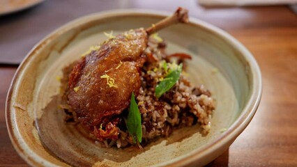 duck confit served with aromatic rice. The tender, flavorful duck and fragrant rice blend harmoniously, offering a sophisticated dish that epitomizes gourmet delight. High quality 4k footage