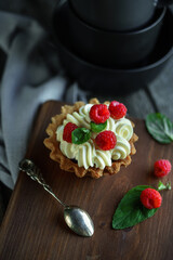 Cake with cream and raspberries with mint leaves on wooden vintage background