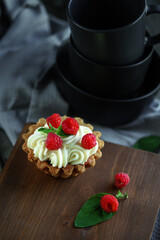 Cake with cream and raspberries with mint leaves on wooden vintage background
