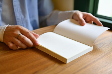 Close-up image of male hand open a empty page of book