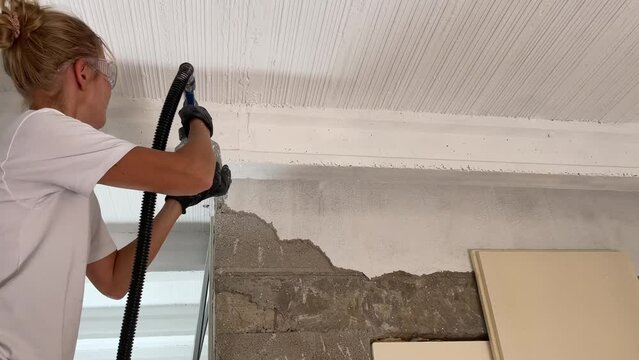 Woman painting the ceiling using the paint sprayer