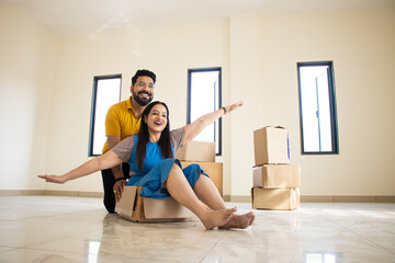 Happy young indian couple having fun in new home. Playing with boxes, Real estate, residential...