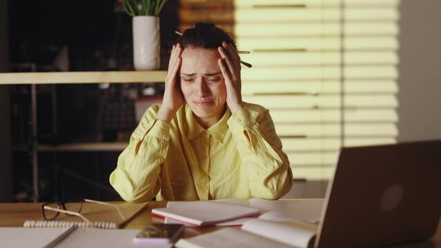 Worried nervous young woman freelancer crying having problems with work at light home workplace Stressed self employee feeling exhausted and looking at screen with sad face Nervous breakdown concept