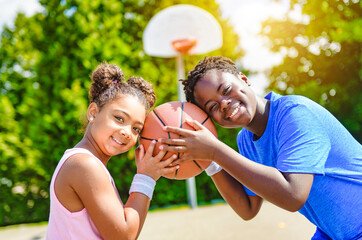 Portrait of brother and sister basketball player standing at basketball court with ball