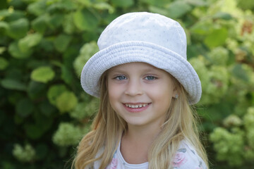 Candid outdoor portrait of happy little girl with bucket hat