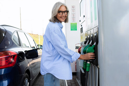 Mature adult woman uses the gas station on her own