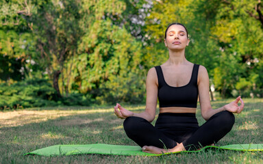 Fototapeta premium beautiful woman practising outdoor yoga in park on fitness mat. female doing stretching, attractive girl doing different poses summer time green nature