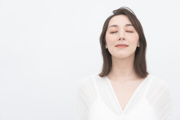 Fototapeta premium 目を閉じて微笑んでいる美しい女性/白背景スタジオ撮影バストアップ