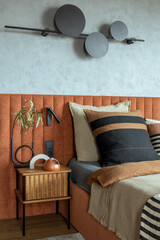 Minimalist composition of bedroom interior with orange bed, beige bedclothes, wooden night stand,...