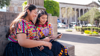 Friends consult information on a smart device sitting in a local park.
