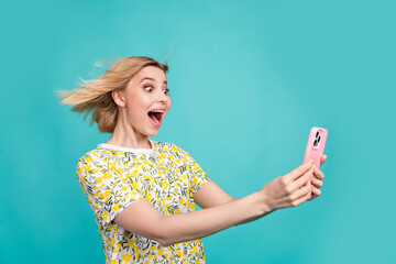 Photo of funky excited girl dressed yellow print t-shirt chatting modern gadget isolated teal color...