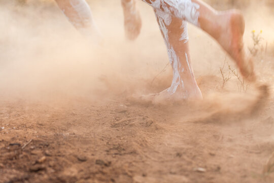 Feet of First nations people dancing in oka paint to tell the story kicking up dust