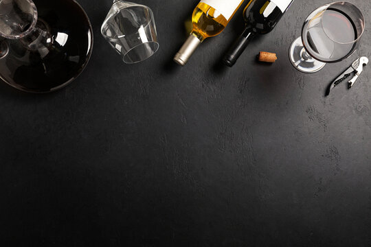 Decanter, glass and bottles with red and white wine on black background