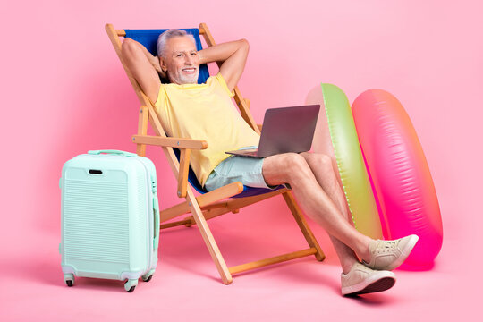 Full body photo nap sleepy senior man hands head lying sunbed comfort watching netbook business course isolated on pink color background