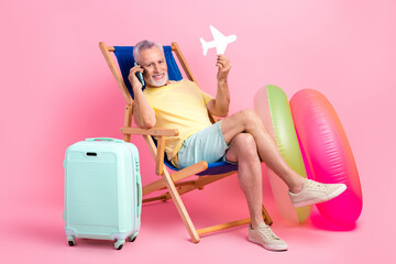 Full body cadre of cheerful satisfied relax pensioner man holding paper airplane call his tour operator isolated on pink color background