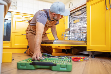 A man repairs a dishwasher - 642097647