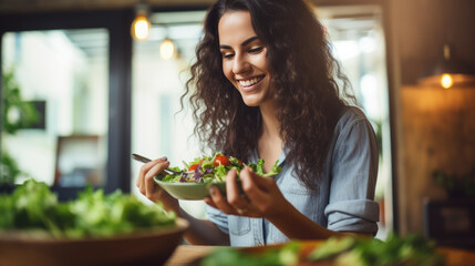 Young athletic woman eats a salad in her plate while eating breakfast