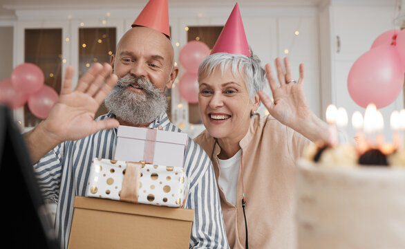 Happy birthday, video call and senior couple celebrate with cake in a home party, event and candles in a house together. Man, woman and elderly excited for virtual or remote surprise on retirement