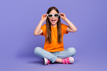Full size body photo of crazy laughing schoolgirl orange t shirt jeans 3d goggles weekend movie watch isolated on violet color background