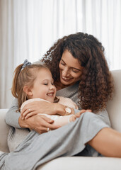 Love, hug and mother with girl child on a sofa happy, playing and bonding in their home together. Family, smile and kid with mom in a living room embrace, relax and enjoy weekend, day off or break