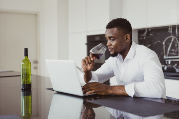 African black lonely business man feel tired exhausted sitting working online amd drinking wine...