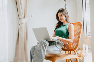 young woman happy smiling typing at laptop computer relax indoor at home living room. people...