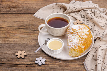 Good morning concept. Breakfast with cup of coffee and fresh croissant. Sweet creamy sauce