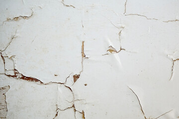 Grunge style urban weathered shabby white peeled painted concrete surface of the wall with holes, dirty and cracks