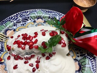 Mexican food Chile en Nogada in a plate and a ribbon.