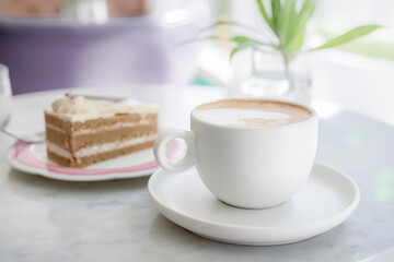 A delicious snack and a mug of hot cappuccino coffee. A piece of cake on the table is a great opportunity to take a break in the afternoon for a pleasant snack.