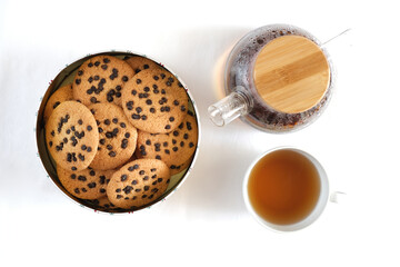 American cookies in a tin with a cup of tea top view on a white background