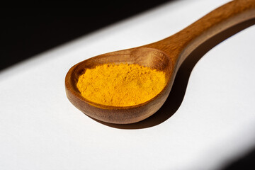 A wooden spoon with yellow turmeric.