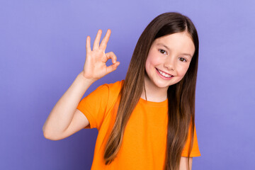 Photo of toothy beaming schoolkid with straight hair dressed orange t-shirt showing okey good work...