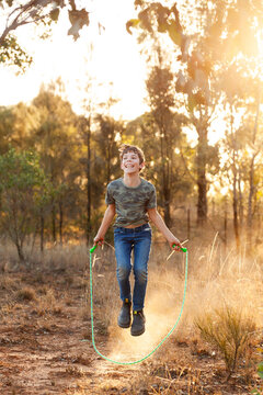 Happy kid skipping with jump rope in golden Australian light