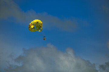 vacaciones en Cancún, parapente amarillo con cielo azul y nubes, verano divertido.