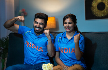 Indian couples celebrating indias win while watching live cricket sports match on tv or television...