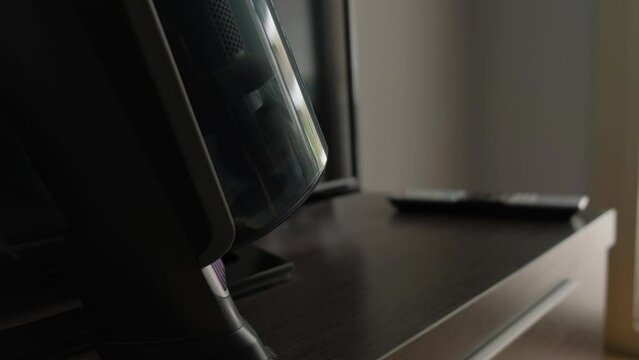 A cordless vacuum cleaner cleans dust on furniture close-up.