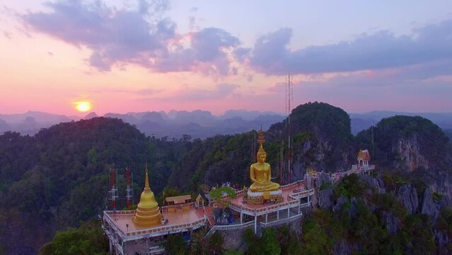 Aerial view is amazing sky at sunset behine The golden buddha on the top of high mountain. .It is more interesting temple complexes in Krabi Thailand, .as the monks live and worship within a maze of n