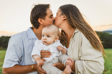 Happy family with baby boy on nature sunset