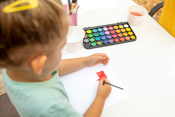 Child painting and drawing with watercolor paint