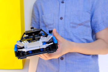 child, boy of 10 years old assembles blue car from blocks parts, educational constructor, concept development fine motor skills, training patience, logic, blocks logo on background, Frankfurt - July 2022