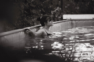 young woman inside a swimming pool in summer garden, summer leisure, relaxation on nature concept