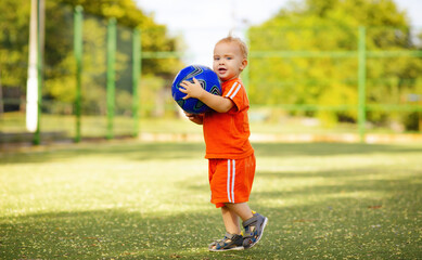 child on a football field, little boy playing ball, active summer leisure and sport concept