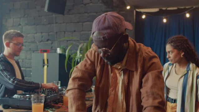 Selective focus portrait of young African American squatter dancing with eyes closed at party with friends in abandoned house