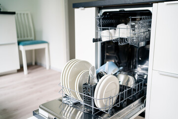 Dish washing machine. Washer in kitchen. Open dishwasher in modern white home. Full of clean plates. House interior and household technology. Tableware and utensils. Water and energy.